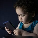 boy in blue tank top holding black iphone 5