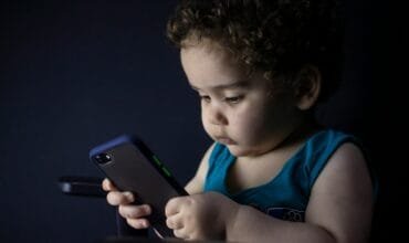 boy in blue tank top holding black iphone 5