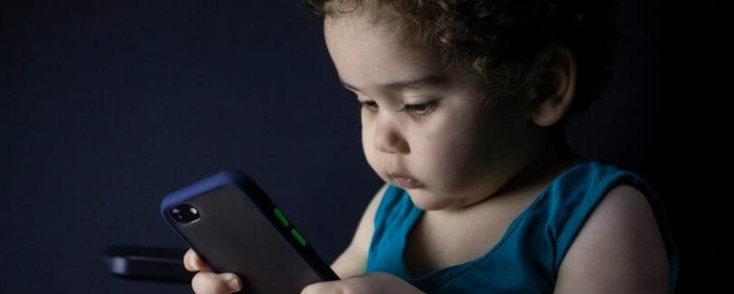 boy in blue tank top holding black iphone 5